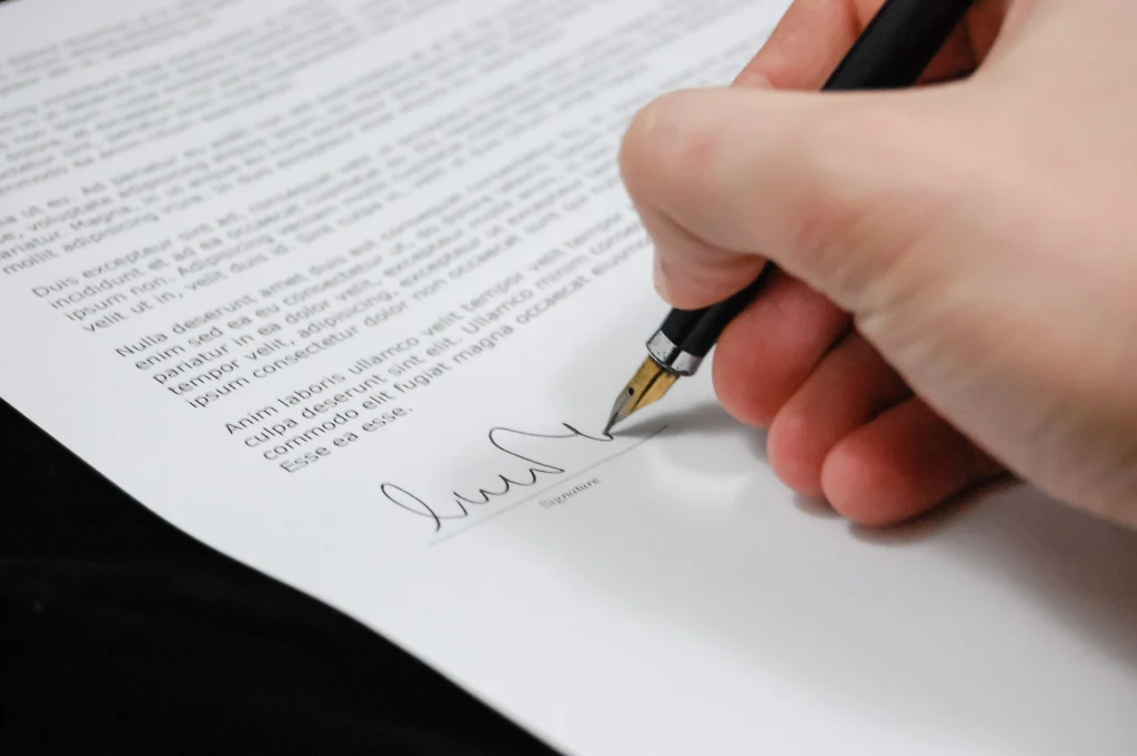 Mână care semnează un document cu stiloul