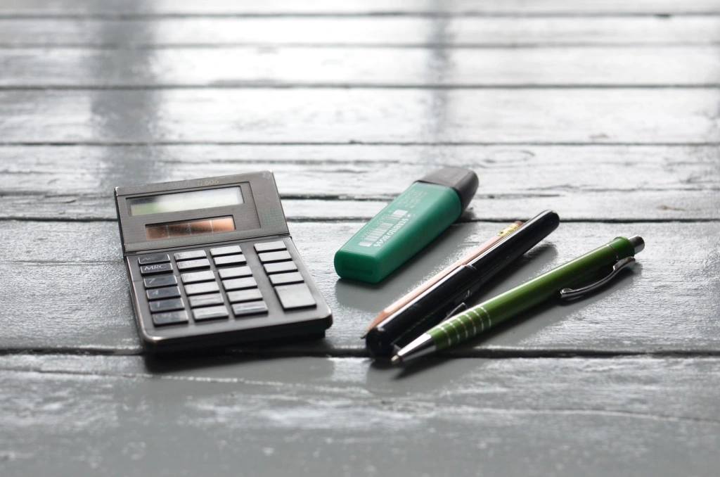 Calculator, marker și pixuri pe un birou din lemn